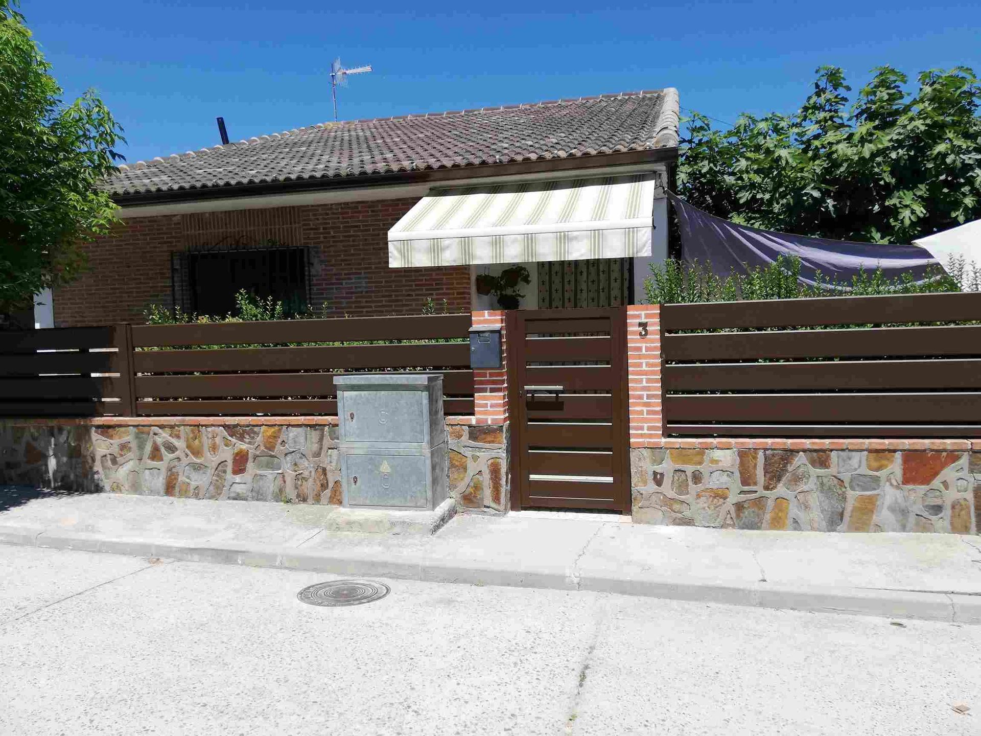 Una casa con una valla de madera y un toldo blanco