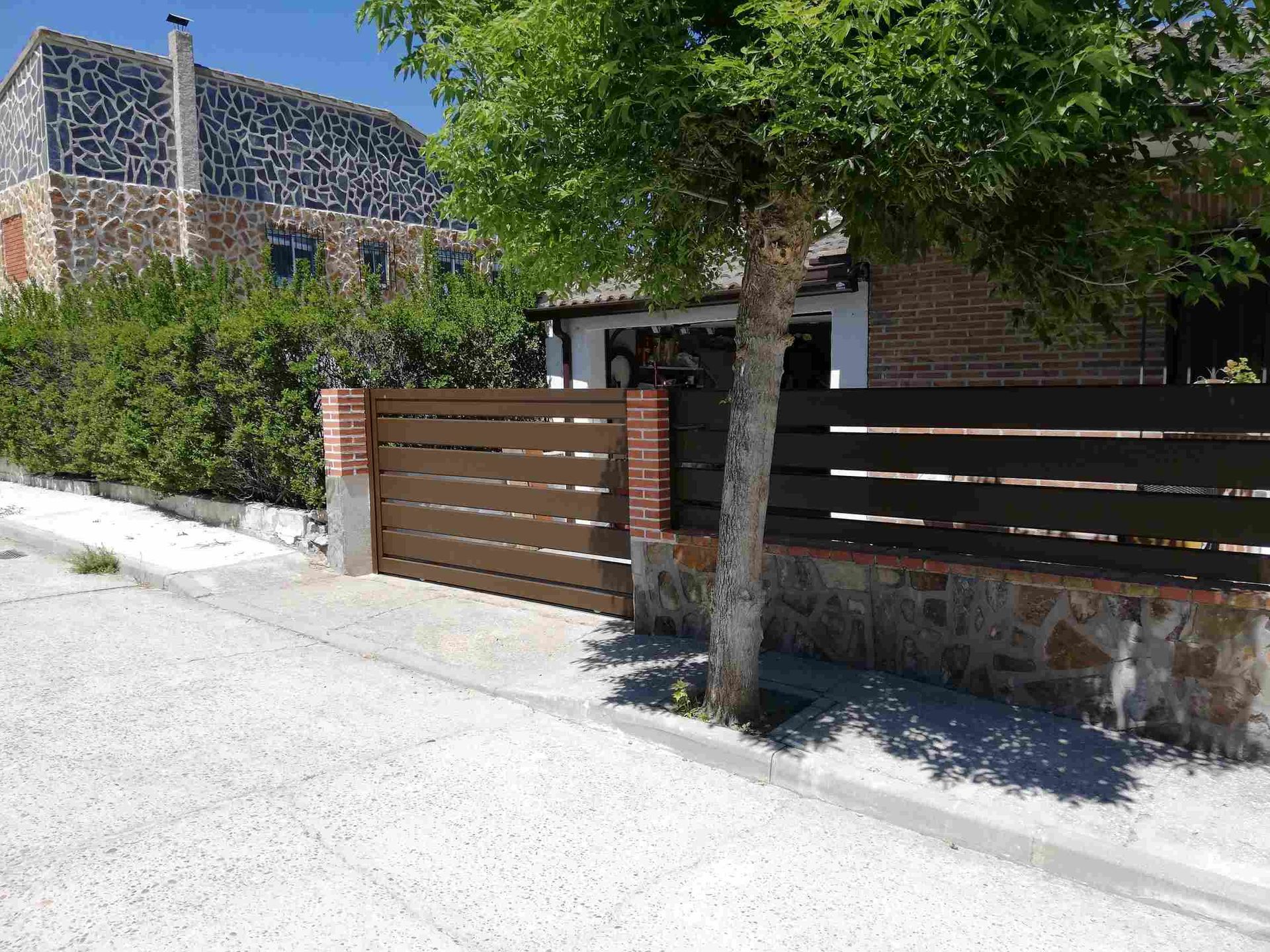 Una casa con una valla de madera y un muro de piedra
