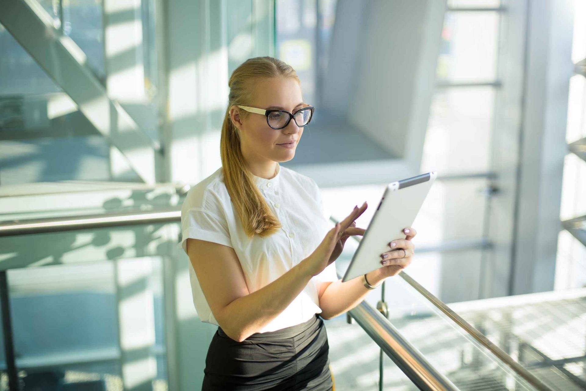 Una mujer está parada en un balcón usando una tableta.