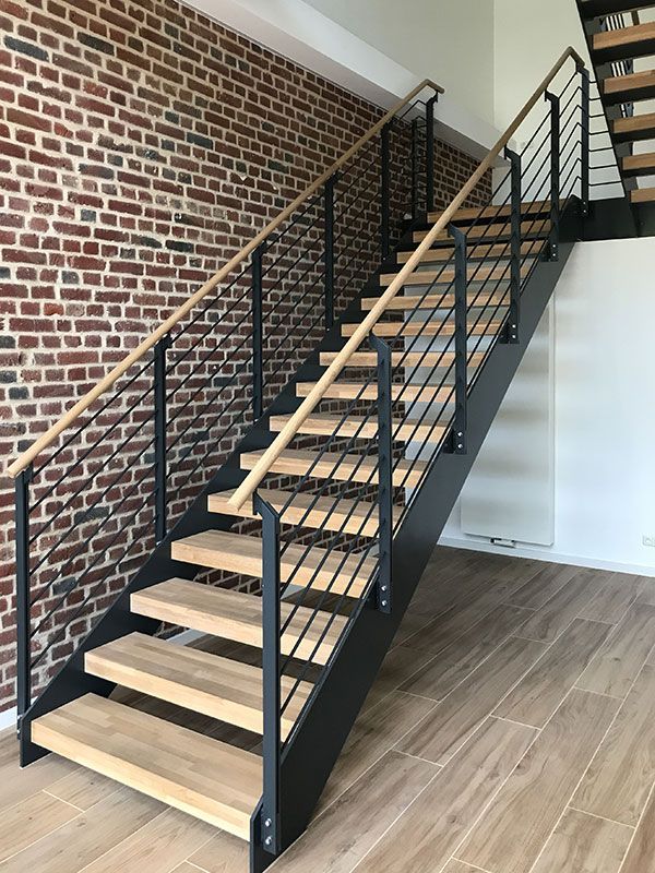 Eine Treppe mit Holzstufen und einem Metallgeländer vor einer Backsteinmauer.