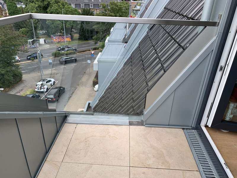 Ein Balkon mit Glasgeländer und Blick auf die Stadt