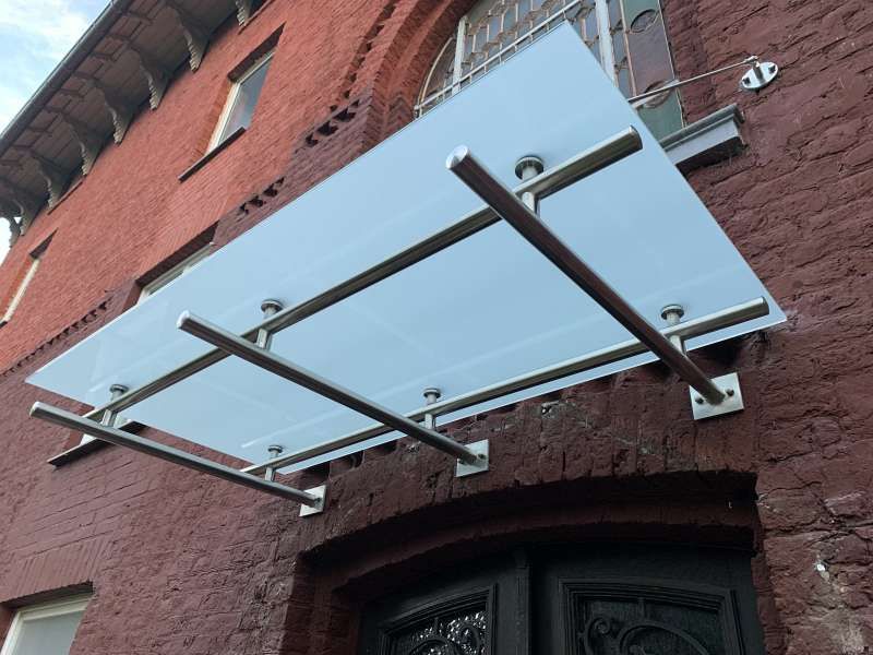 An der Seite eines Backsteingebäudes ist ein Glasdach angebracht.