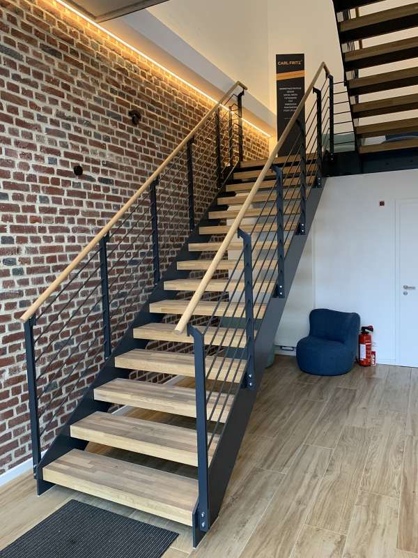 Eine Treppe mit Holzstufen und einem Metallgeländer vor einer Backsteinmauer.
