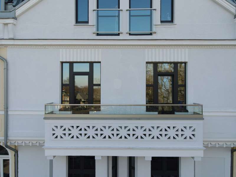 Ein weißes Gebäude mit einem Balkon und vielen Fenstern