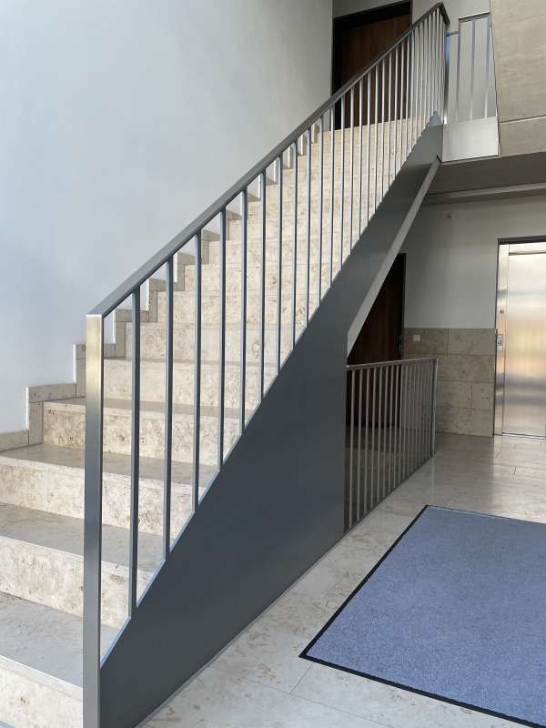 Eine Treppe mit Metallgeländer und blauem Teppich