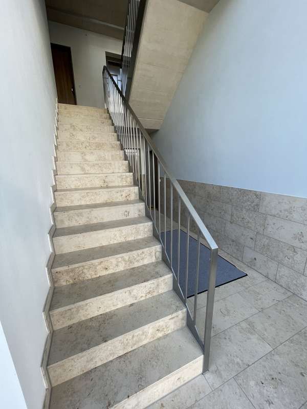 Eine Treppe mit Metallgeländer, die in den zweiten Stock eines Gebäudes führt.