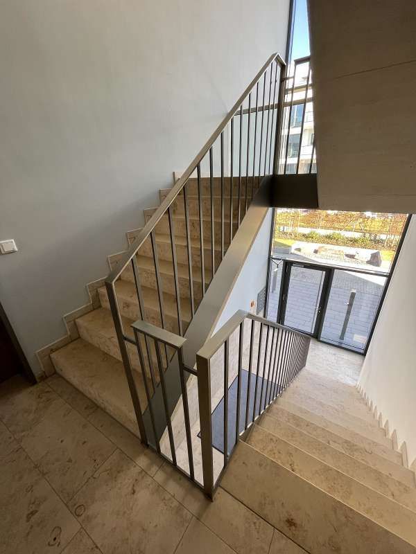 Eine Treppe mit einem Metallgeländer und einem Fenster in einem Gebäude.