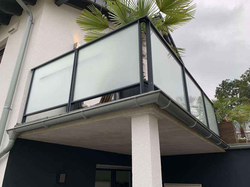 Ein Balkon an der Seite eines Hauses mit einer Palme im Hintergrund