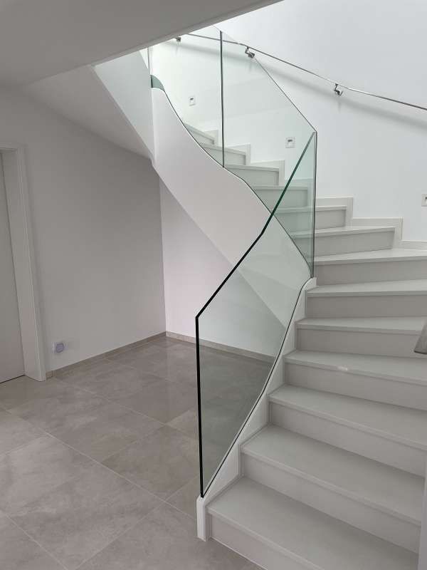 Eine weiße Treppe mit einem Glasgeländer in einem Haus.