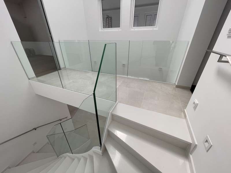 Eine weiße Treppe mit einem Glasgeländer in einem Haus.