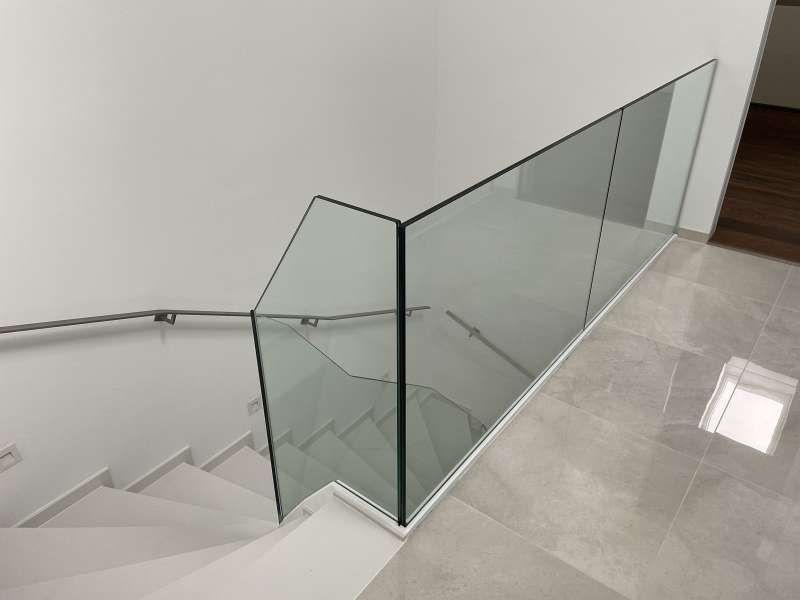 Eine Treppe mit Glasgeländer und Edelstahlhandlauf.