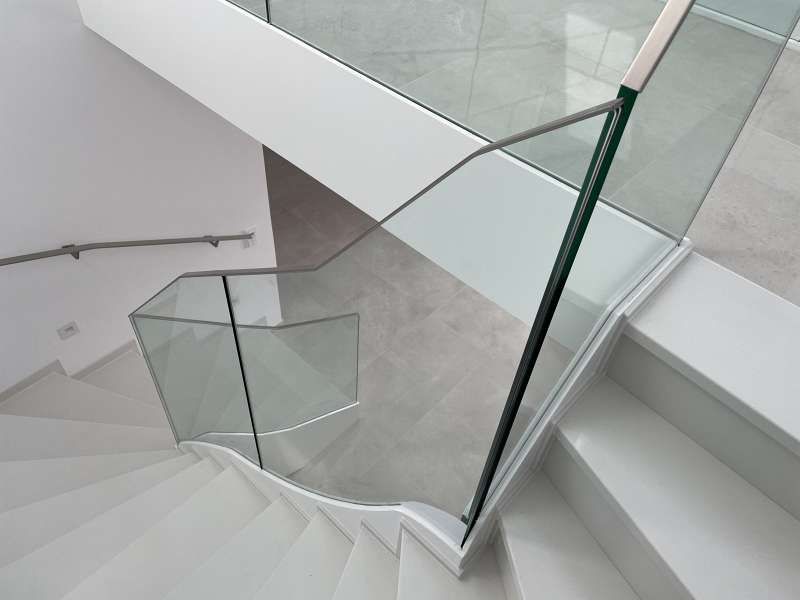 Eine Treppe mit Glasgeländer und weißen Stufen