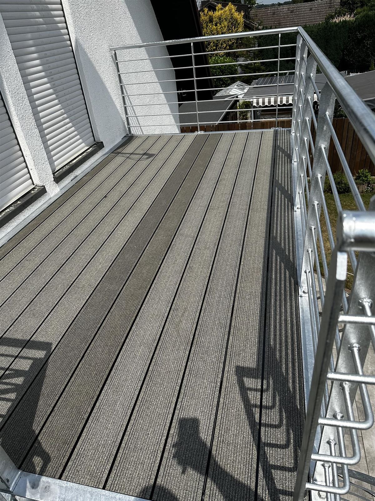 Ein Balkon mit Edelstahlgeländer und Holzterrasse.