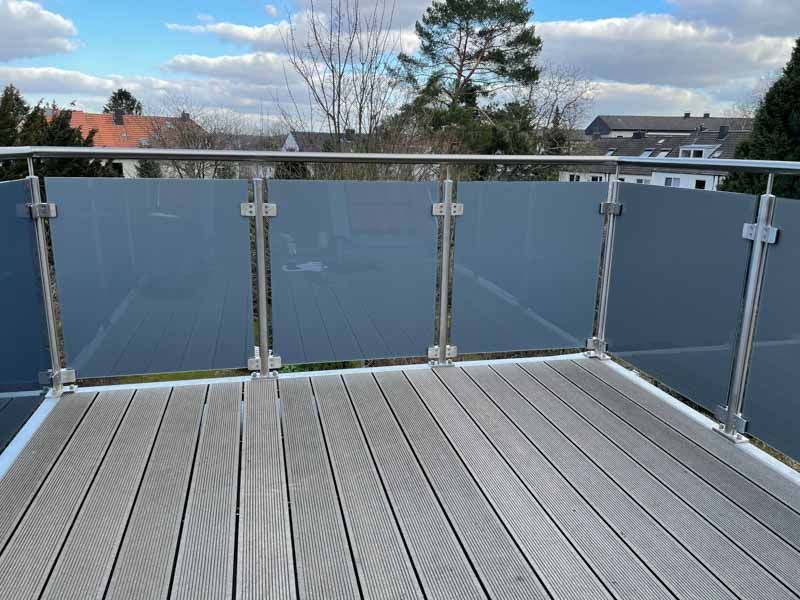Ein Balkon mit Edelstahlgeländer und Holzterrasse.
