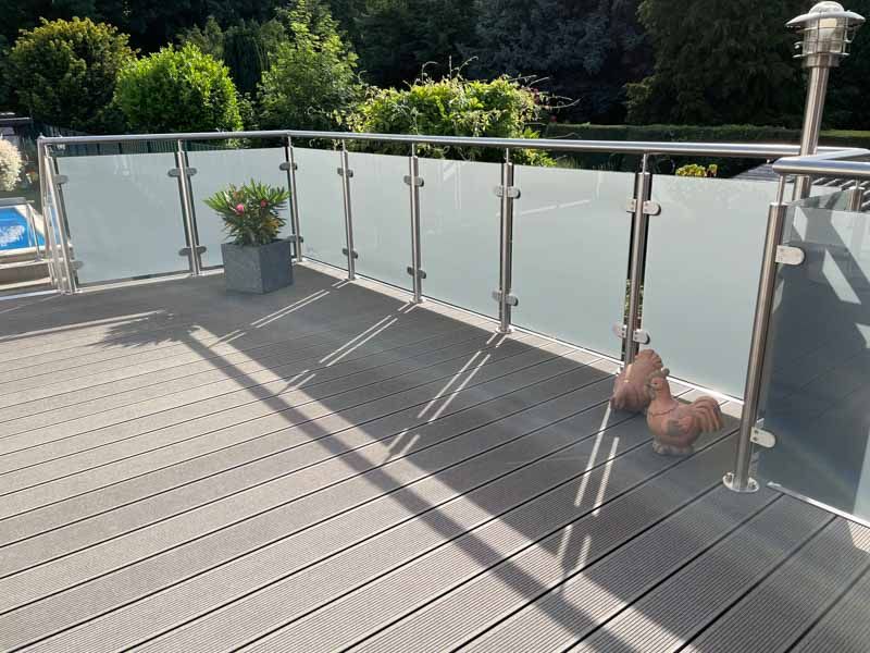 Ein Balkon mit einem Glasgeländer und einer Topfpflanze darauf