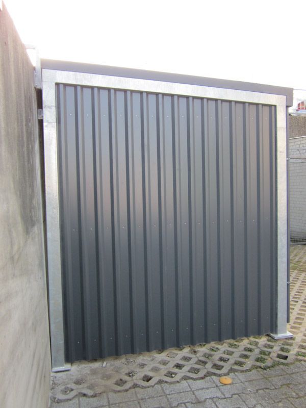 Ein graues Garagentor steht auf einem Gehweg neben einer Wand.