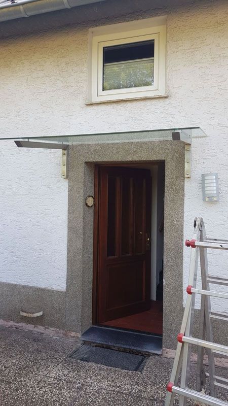 Ein weißes Haus mit einer Holztür und einem Fenster.