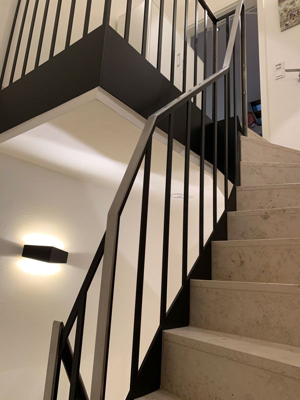 Eine Treppe mit schwarzem Geländer und weißen Stufen
