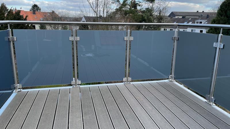 Ein Balkon mit Edelstahlgeländer und Holzterrasse.