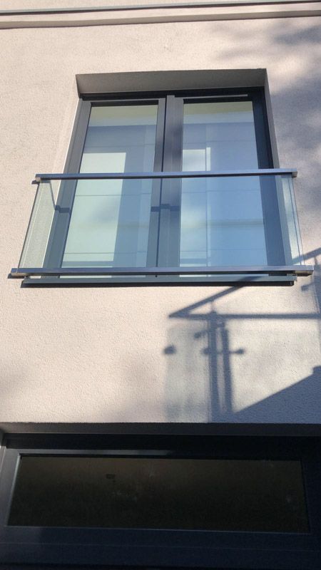 Ein Fenster mit einem Glasgeländer an der Seite eines Gebäudes
