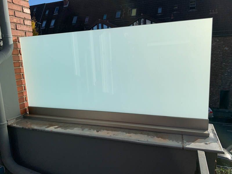 Eine weiße Tafel steht auf einem Sims neben einem Backsteingebäude.