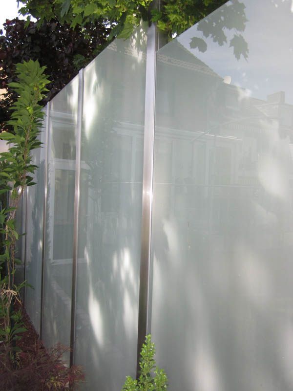 Ein weißer Glaszaun mit einem Edelstahlpfosten