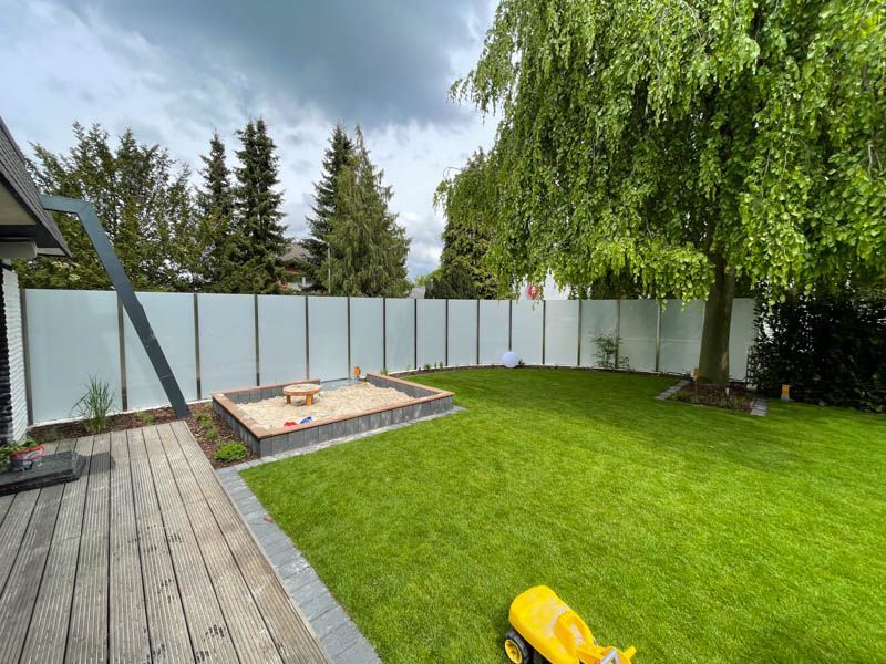 Ein Hinterhof mit Sandkasten und weißem Zaun.