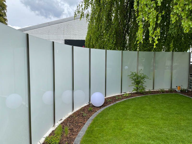 Ein weißer Zaun umgibt einen üppigen grünen Rasen in einem Hinterhof.