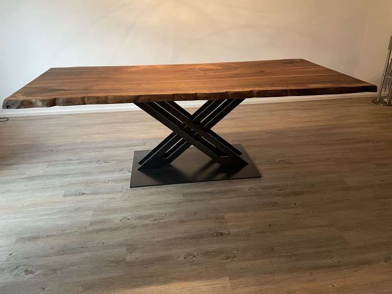 Ein Holztisch mit Metallgestell steht auf einem Holzboden.