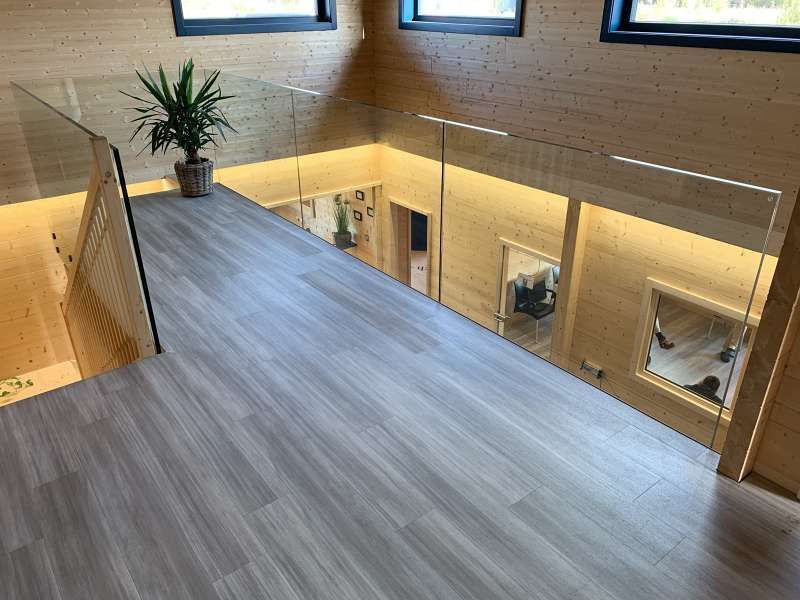 Eine Treppe mit Glasgeländer und einer Pflanze auf dem Boden.