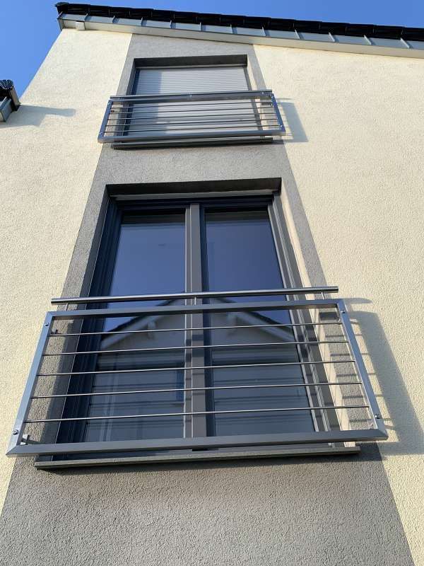 Ein Gebäude mit drei Fenstern und einem Metallgeländer