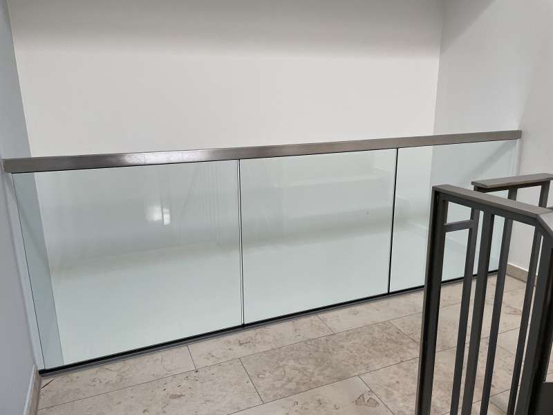 Eine Treppe mit Glasgeländer und weißer Wand.