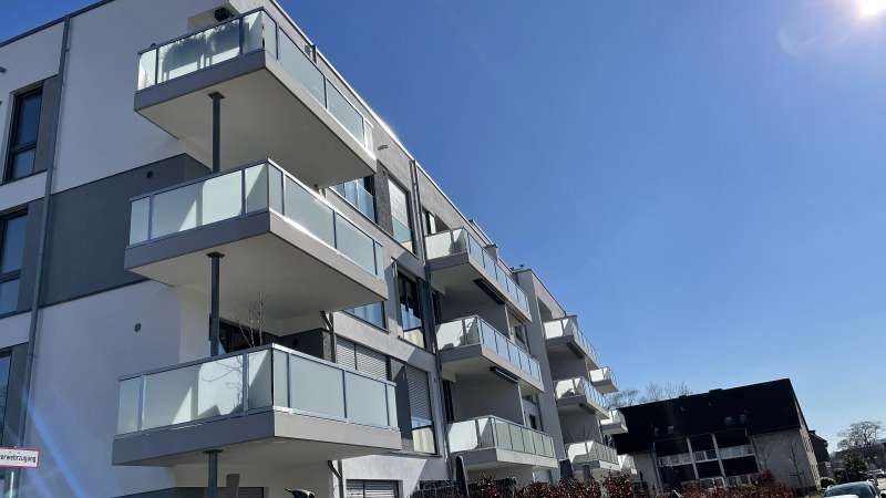 Ein großes Wohnhaus mit Balkonen und einem blauen Himmel im Hintergrund.