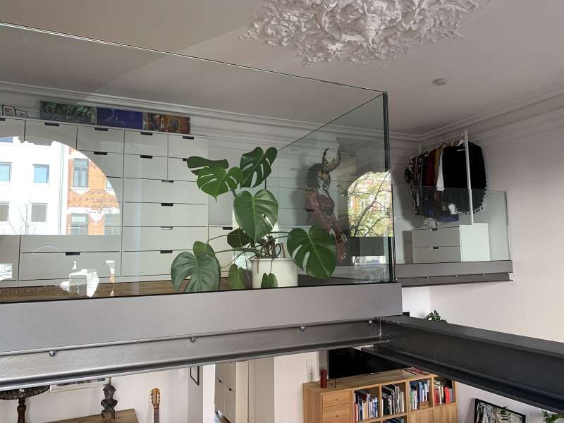 Ein Wohnzimmer mit Balkon und Glasgeländer.