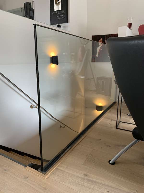 Eine Treppe mit Glasgeländer und schwarzem Stuhl