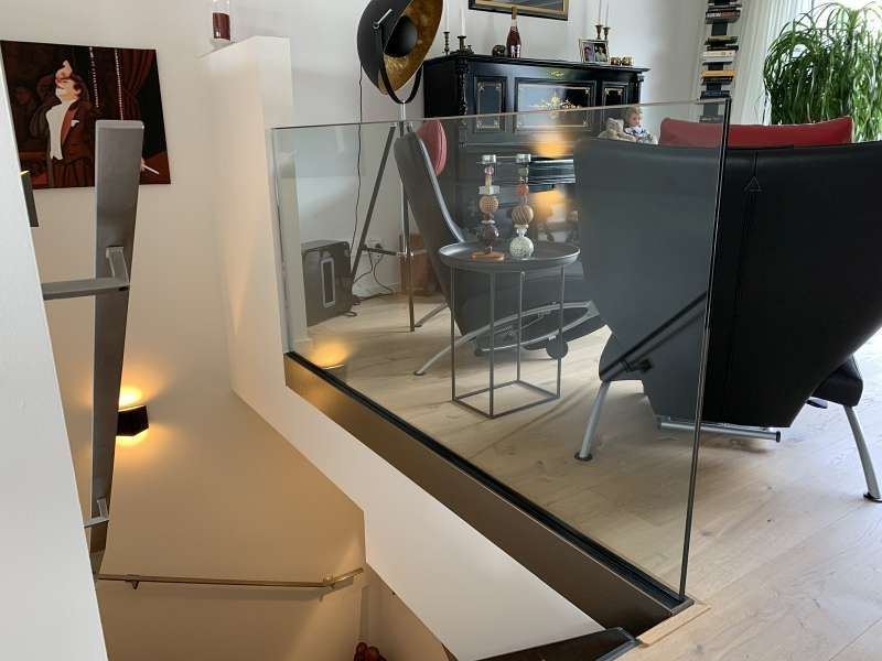 Ein Wohnzimmer mit einer Treppe und einem Glasgeländer