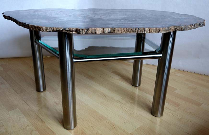 Ein Tisch mit Glasplatte und Metallbeinen auf einem Holzboden