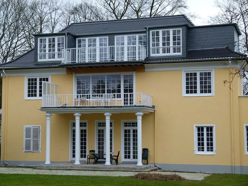 Ein großes gelbes Haus mit einem Balkon und vielen Fenstern