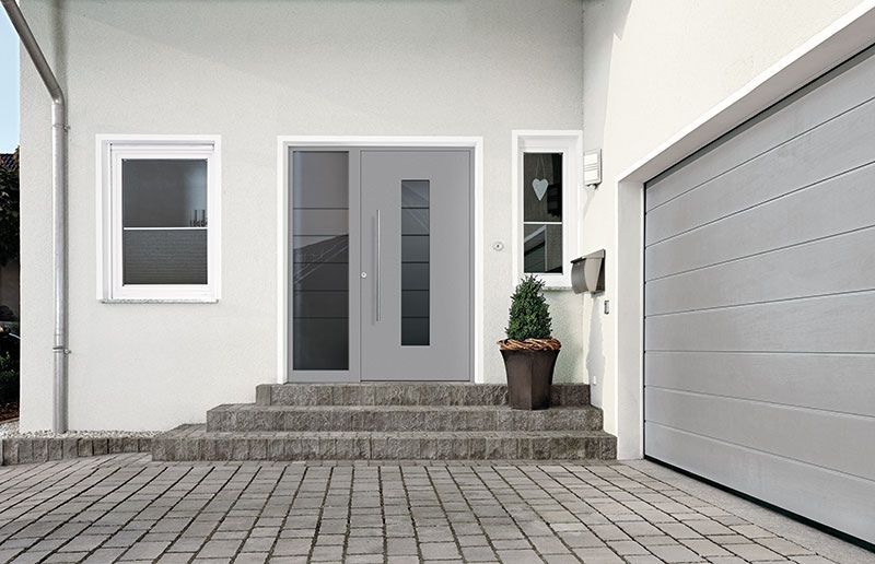 Ein weißes Haus mit einer grauen Tür und einem Garagentor.