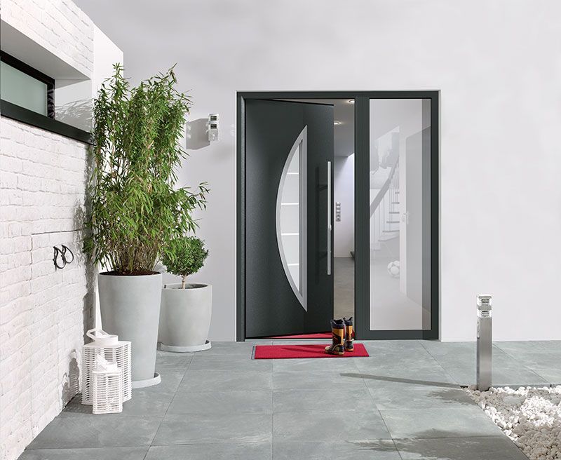 Die Haustür eines Hauses hat einen schwarzen Rahmen und eine Glasplatte.