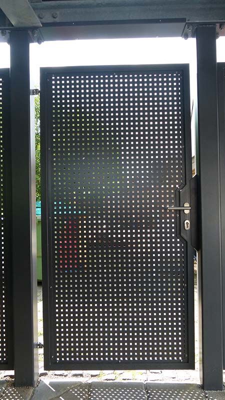 Ein schwarzes Metalltor mit Löchern darin ist offen