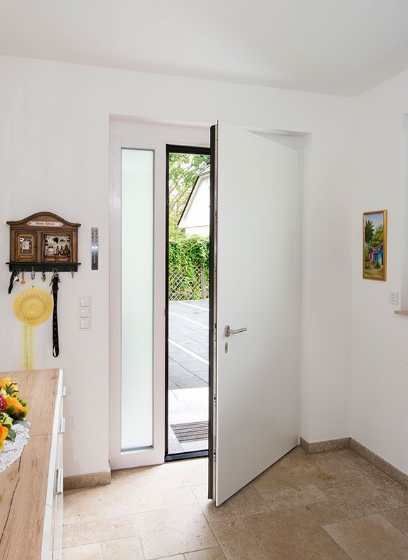 Eine weiße Tür steht in einem Raum offen, an dessen Wand eine Uhr hängt.