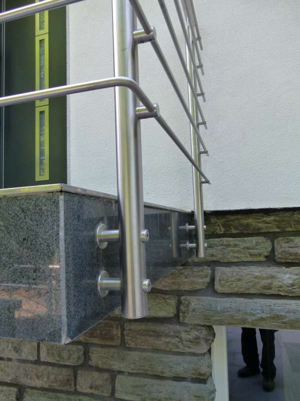 Ein Edelstahlgeländer ist an einer Ziegelwand befestigt