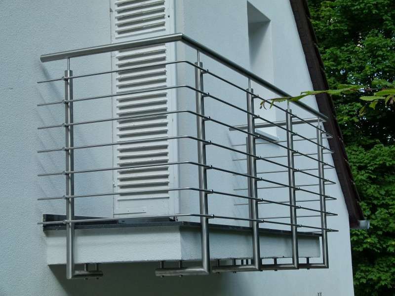 Ein Balkon mit einem Edelstahlgeländer an der Seite eines Gebäudes