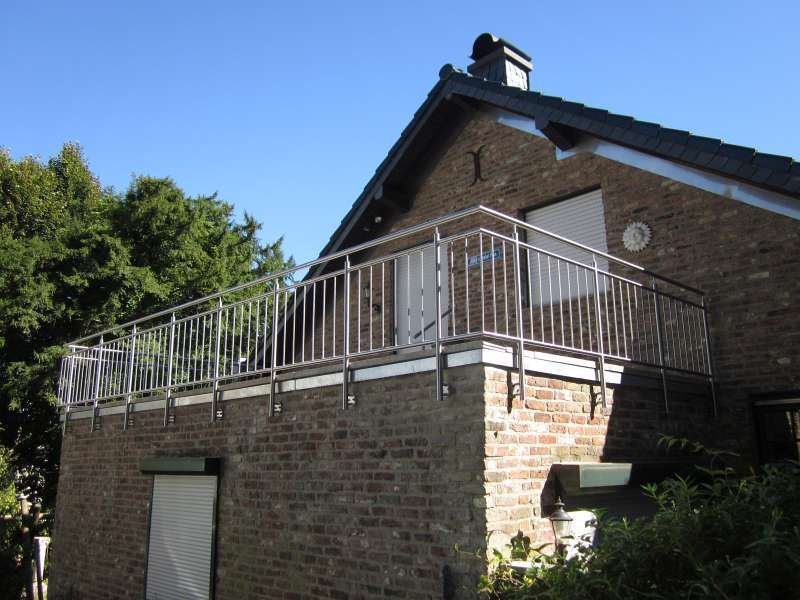 Ein Backsteinhaus mit einem Balkon mit einem Edelstahlgeländer
