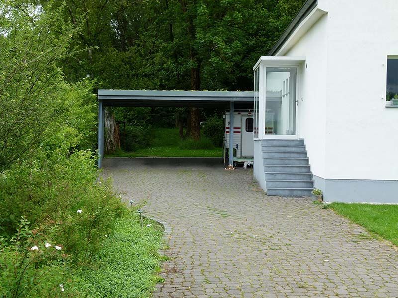 Ein weißes Haus mit einem Carport davor.