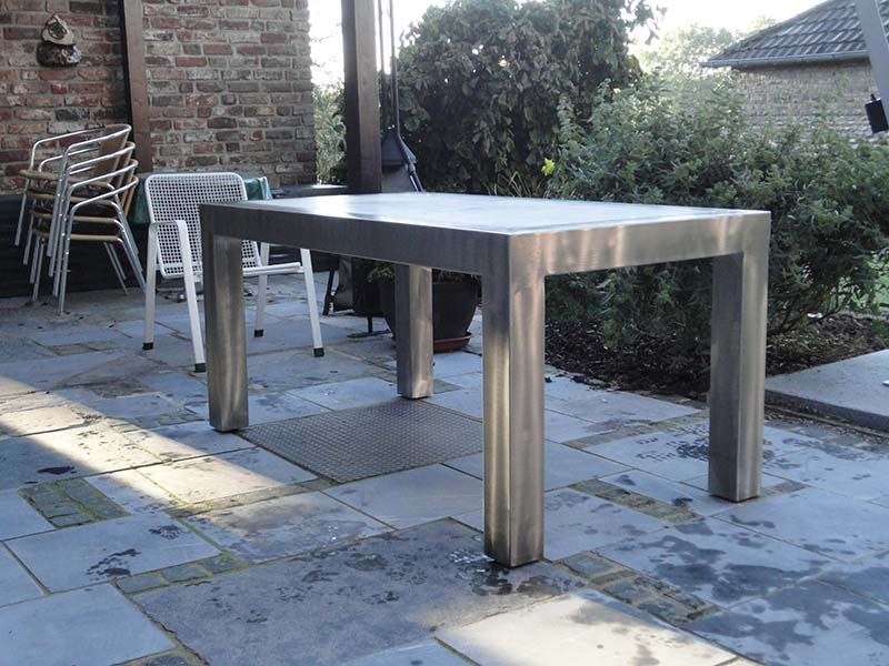 Ein Edelstahltisch steht auf einer Terrasse vor einem Backsteingebäude