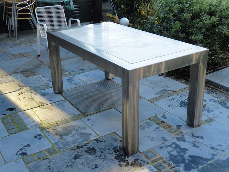 Ein Edelstahltisch steht auf einer gefliesten Terrasse