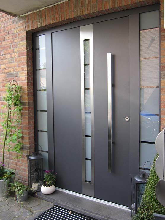 Eine schwarze Haustür mit einem Edelstahlgriff und einer Ziegelwand.