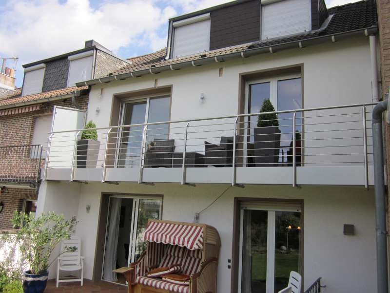 Ein weißes Haus mit Balkon und gestreiftem Stuhl